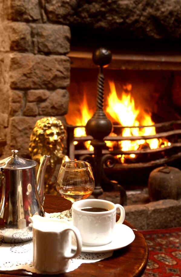 Una habitación acogedora con chimenea, una mesa con tetera, vaso y tazas.