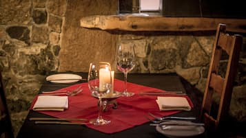 Une table mise pour deux personnes, avec une bougie, un verre à vin et des couverts.