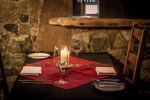 Una mesa para dos, con una vela, una copa de vino y cubiertos.