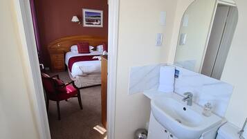 A hotel room with a bed, a bedside table, a mirror, a sink, and a toilet.