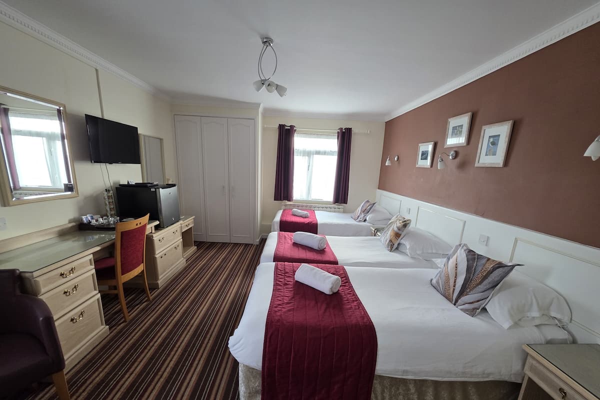 A hotel room with two beds, a desk, a chair, a television, and a wardrobe.