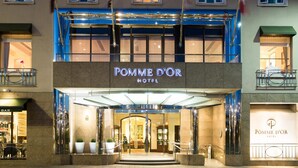 The exterior of the Pomme d'Or Hotel with a prominent entrance, flags, and a well-lit facade. - Pomme d'Or Hotel (St. Helier)