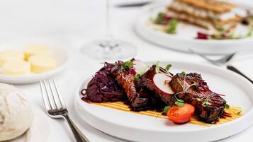 A plate of food with a fork and a glass of wine on a table.