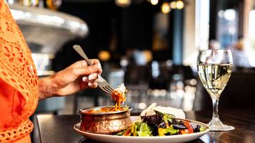 En person spiser på restaurant med en tallerken mad og et glas hvidvin.