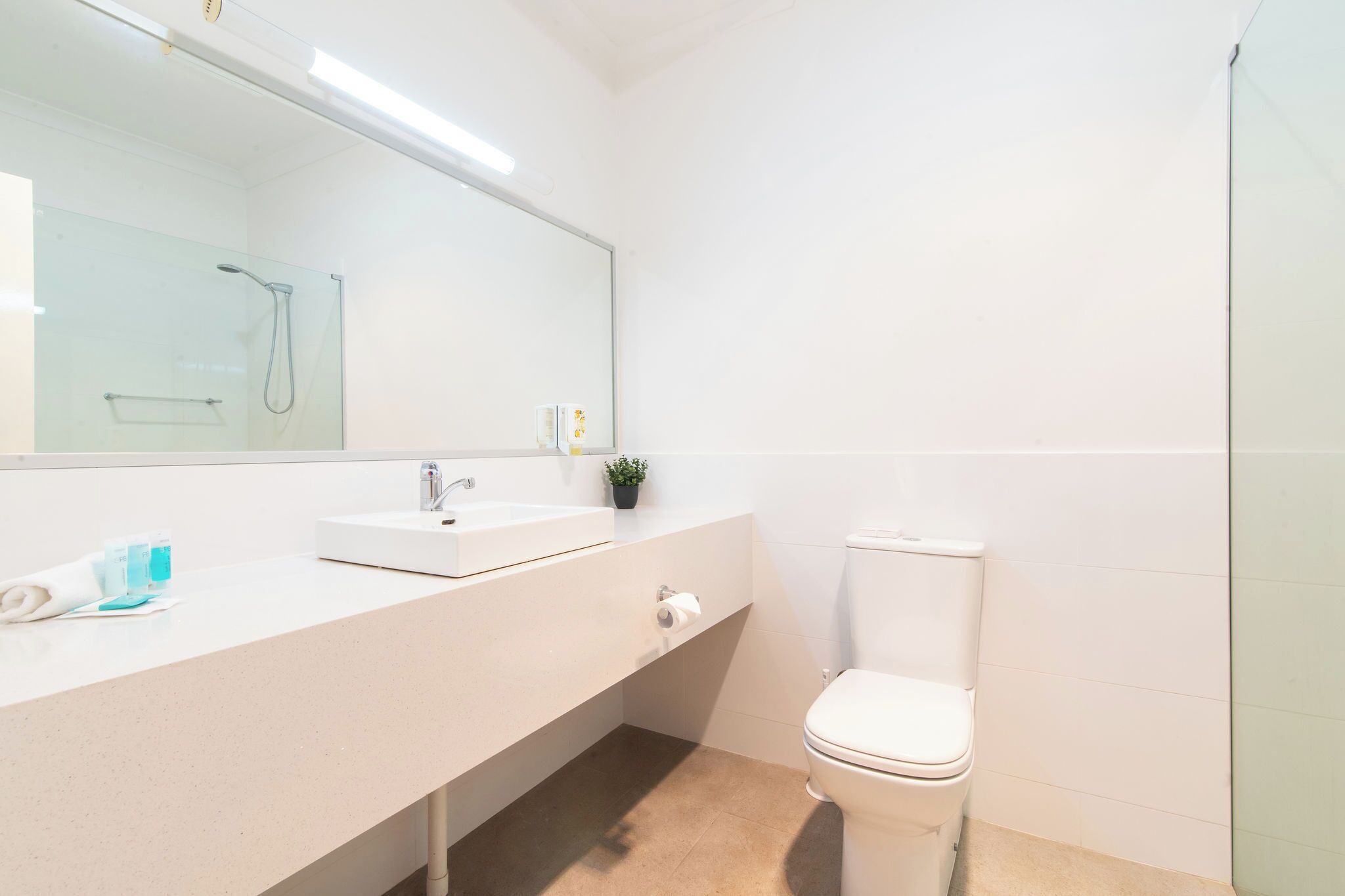 A modern bathroom with a white sink, mirror, and toilet.