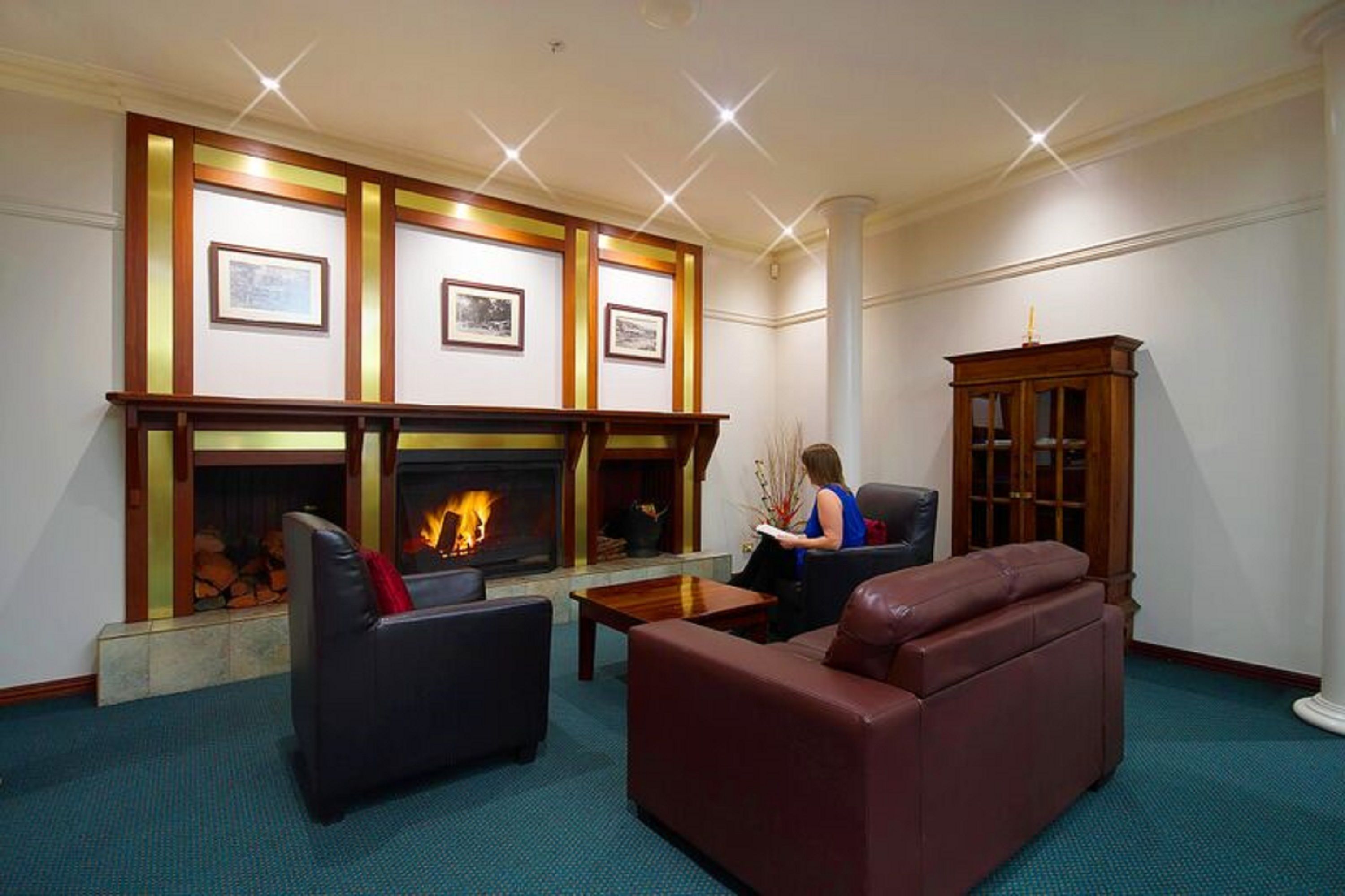 Eine gemütliche Lobby mit Kamin, Ledersofas und gerahmten Bildern an der Wand.