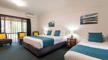 Une chambre d’hôtel avec deux lits, un bureau, une chaise et des œuvres d’art accrochées aux murs.