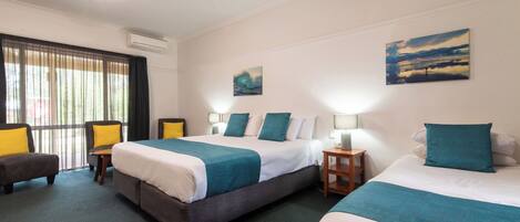 A hotel room with two beds, a desk, a chair, and artwork on the walls.