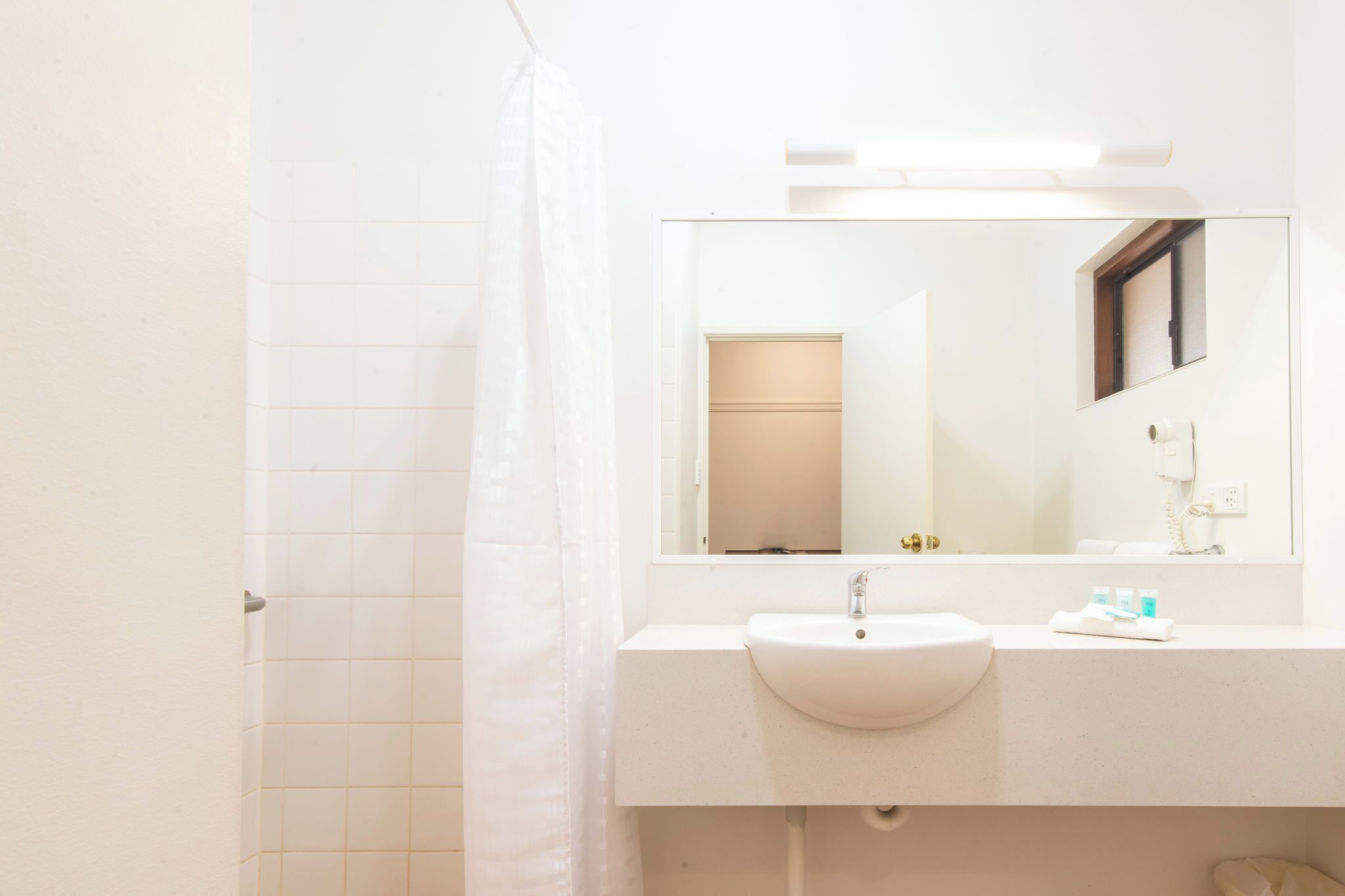 A bathroom with a white sink, a mirror, and a shower curtain.