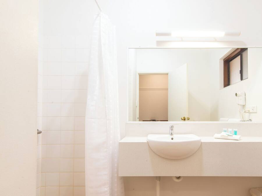 A bathroom with a white sink, a mirror, and a shower curtain.