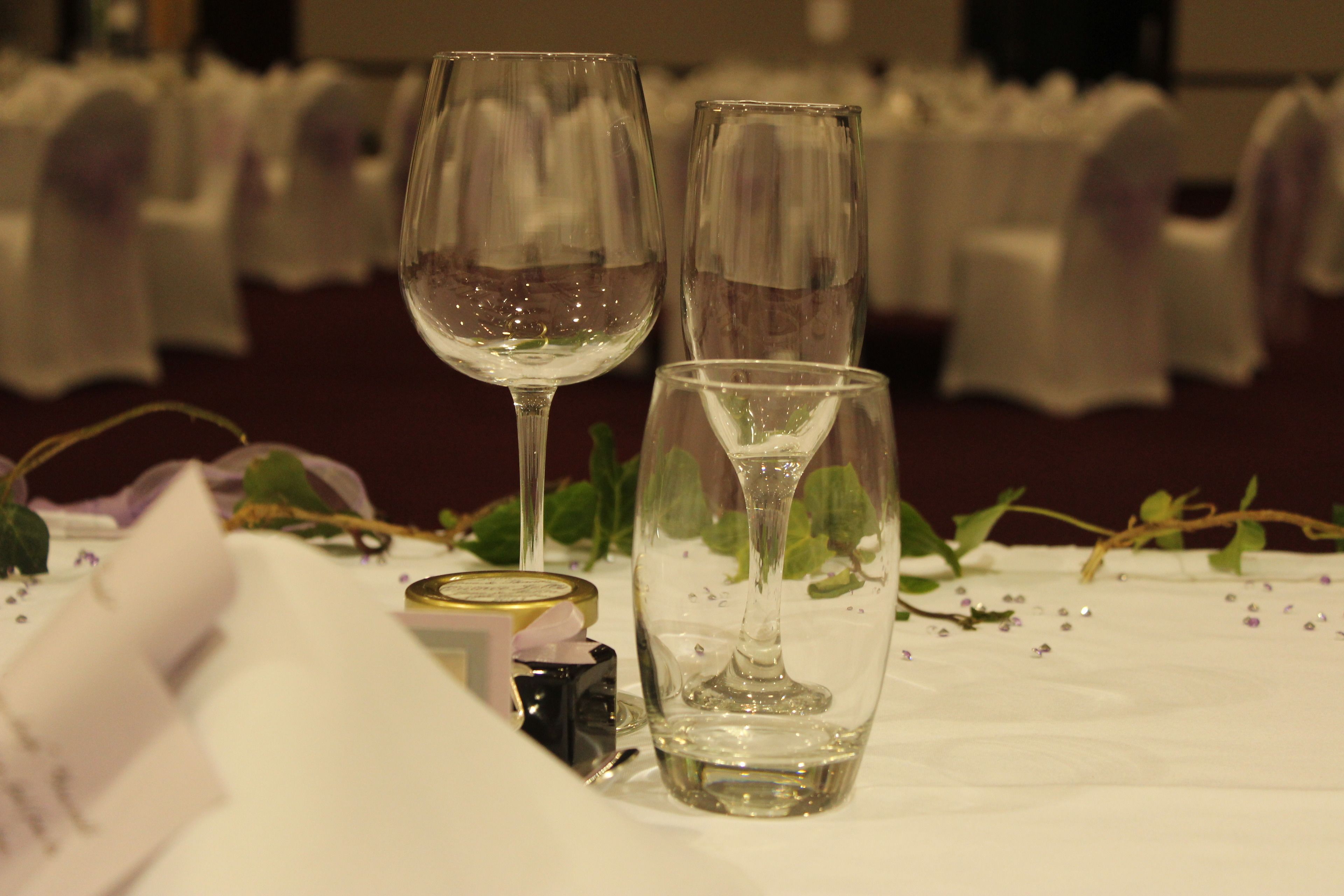 Ein Tisch mit zwei Weingläsern und einem kleinen Behälter, vermutlich für Gewürze, auf einer Tischdecke mit Blumenmuster.