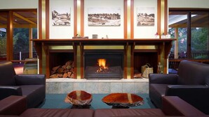 Un salon chaleureux avec une cheminée, deux canapés en cuir et une table basse en pierre.
