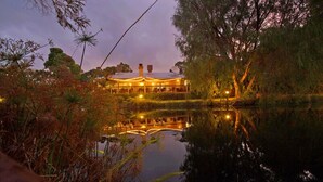 Un bâtiment avec un bassin aux reflets scintillants, entouré d’arbres et de végétation.