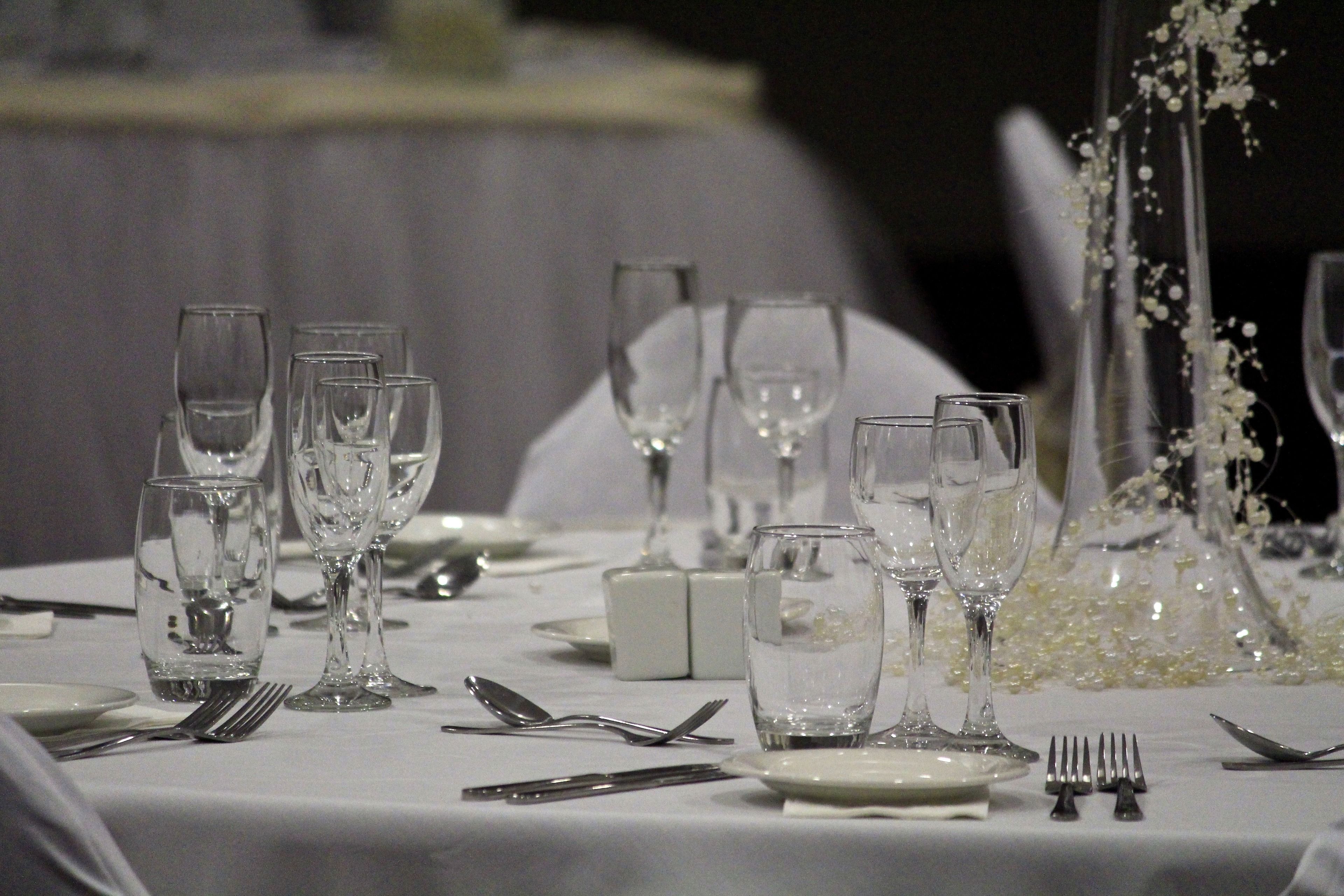 Una mesa dispuesta para una cena formal, con varias copas de vino, platos y cubiertos.