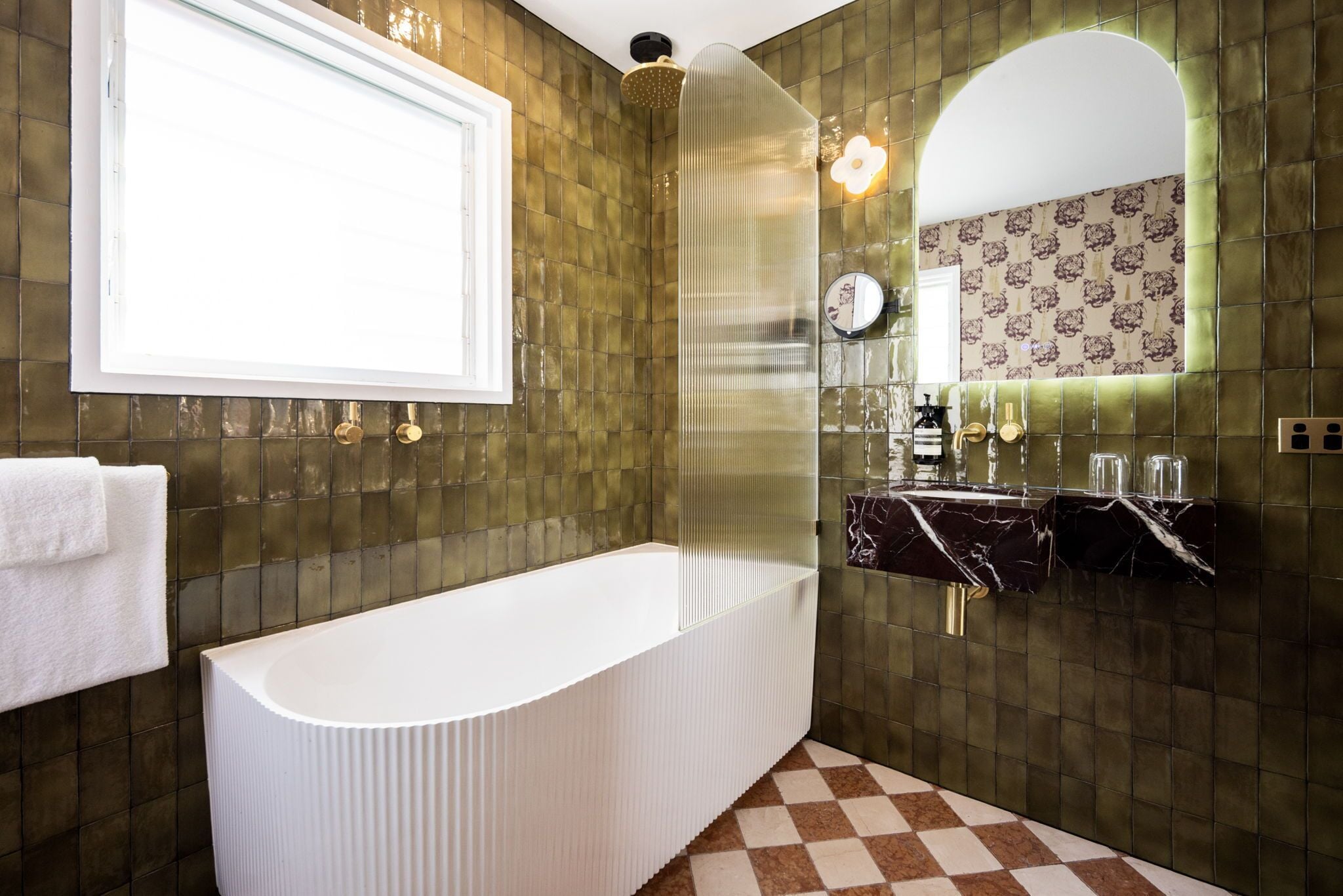 A modern bathroom with a freestanding bathtub, a vanity with a mirror, and a patterned wall.