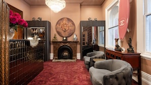 A luxurious room with a fireplace, a chandelier, a mirror, and a red carpet. - Medusa Boutique Hotel (Darlinghurst)