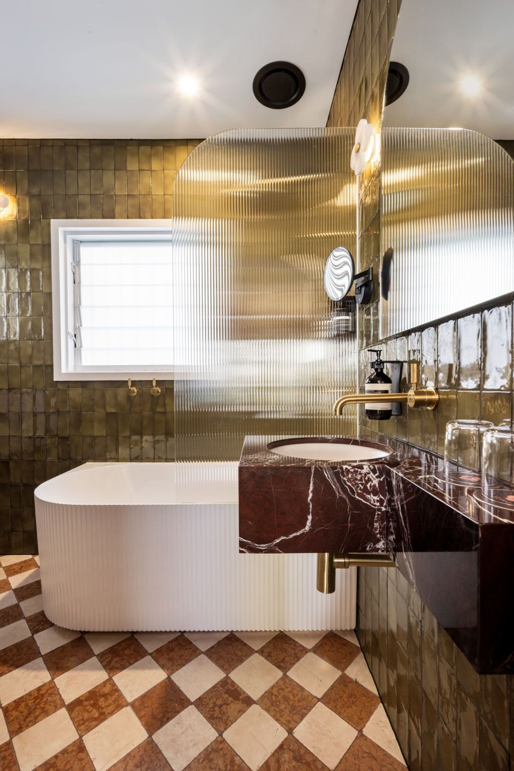 Un bagno moderno con una vasca da bagno indipendente, un mobile lavabo in marmo e un ampio specchio.