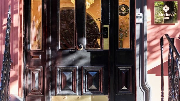 A black double door with a chandelier above, a reception sign, and a Medusa Hotel sign on the wall. - Medusa Boutique Hotel (Darlinghurst)