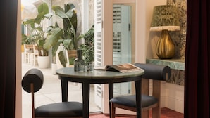 A modern interior with a round table, two chairs, a potted plant, a lamp, and a patterned wall. - Medusa Boutique Hotel (Darlinghurst)