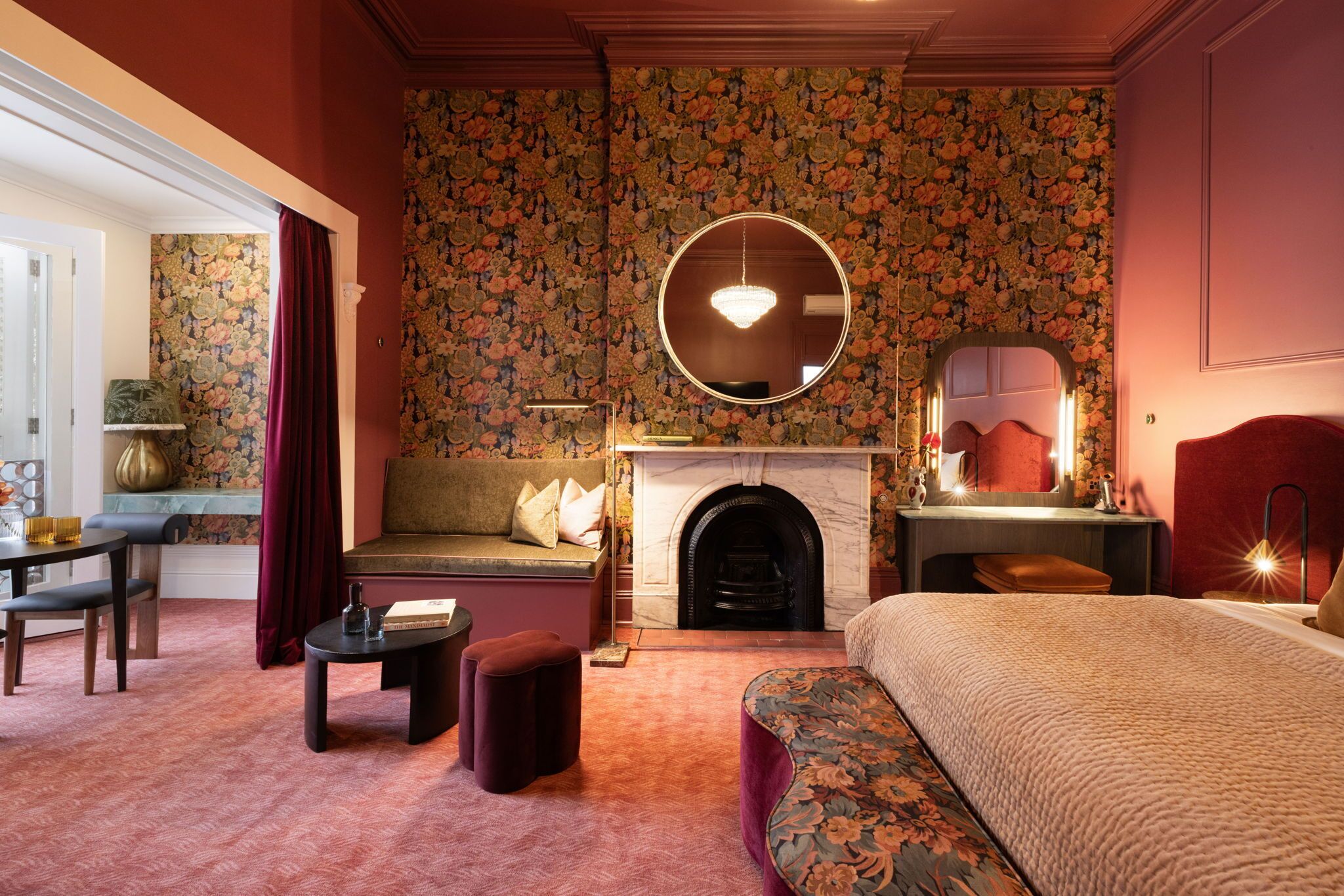 Una habitación con sofá, espejo redondo, chimenea y cama.