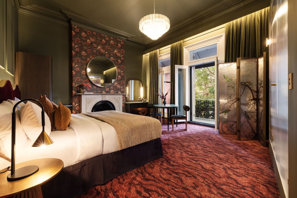 A hotel room with a large bed, a desk, a fireplace, and a view of the outdoors.