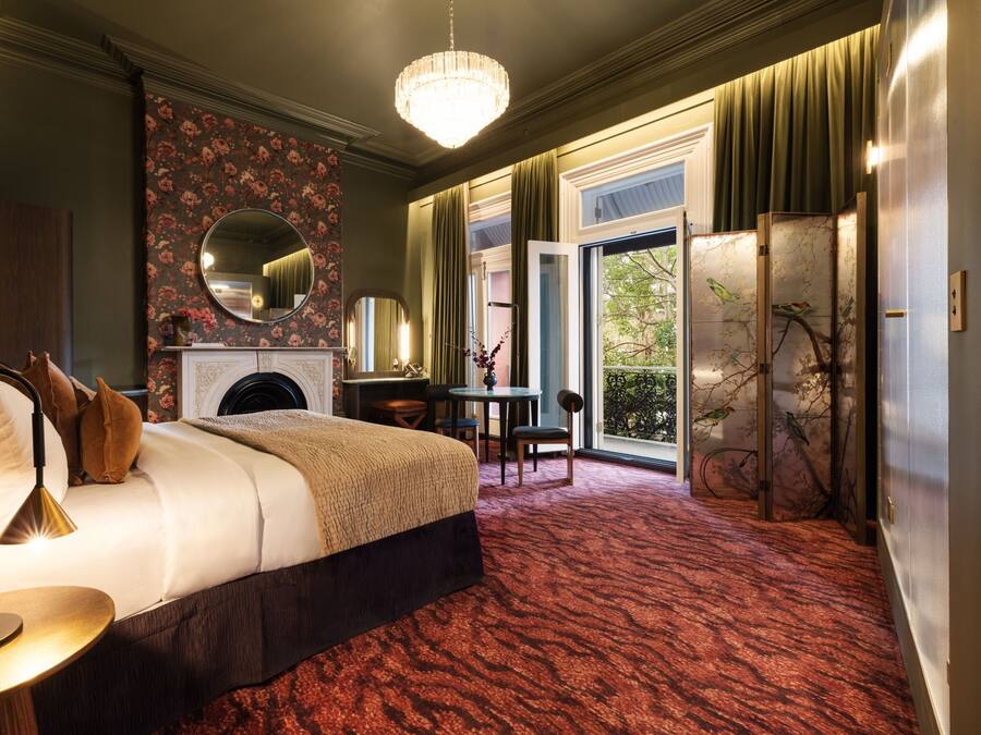 Habitación de hotel con una cama grande, un escritorio, una chimenea y vistas al exterior.