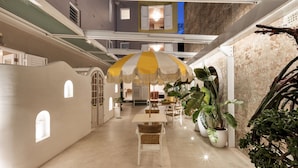A spacious indoor area with a central table and chairs, surrounded by potted plants and a large umbrella. - Medusa Boutique Hotel (Darlinghurst)