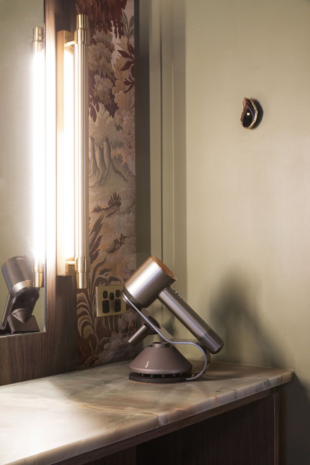 A modern bathroom with a marble countertop, a wall-mounted mirror, and a towel rack.