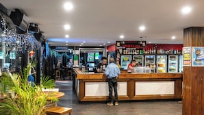 A bar area with a wooden counter, a refrigerated display case, and a seating area with tables and chairs.