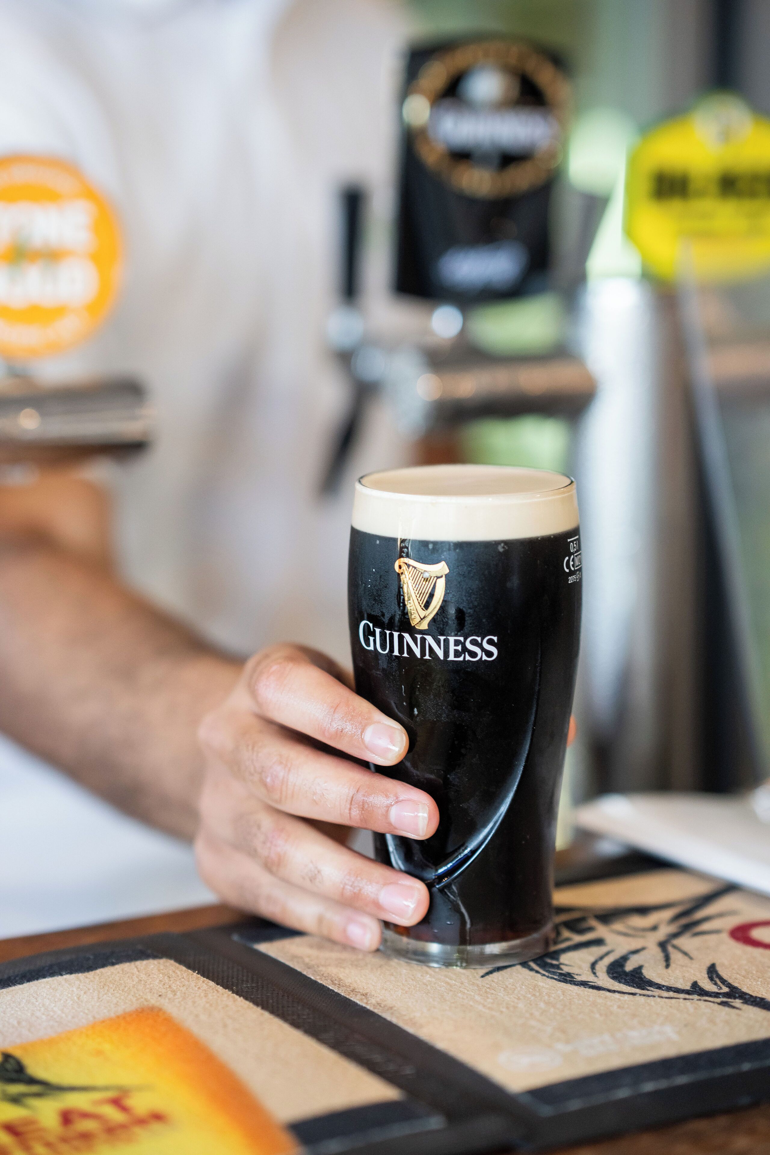 A Guinness glass on a coaster with a logo.