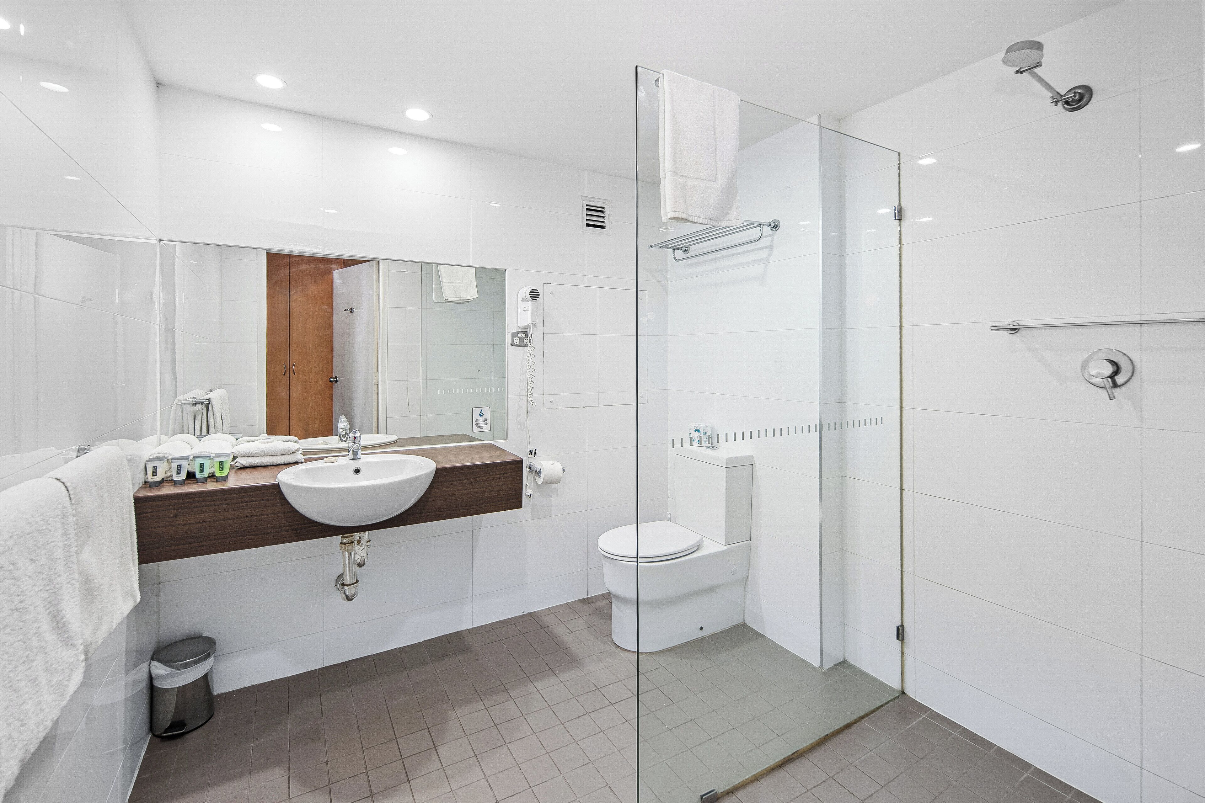 A modern bathroom with a glass shower enclosure, a white sink, and a toilet.