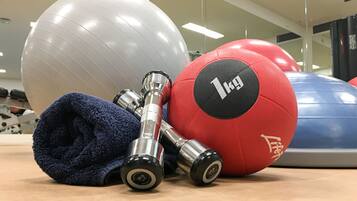 Equipos de ejercicio que incluyen una pelota medicinal roja, una pelota de ejercicio azul y una toalla azul.
