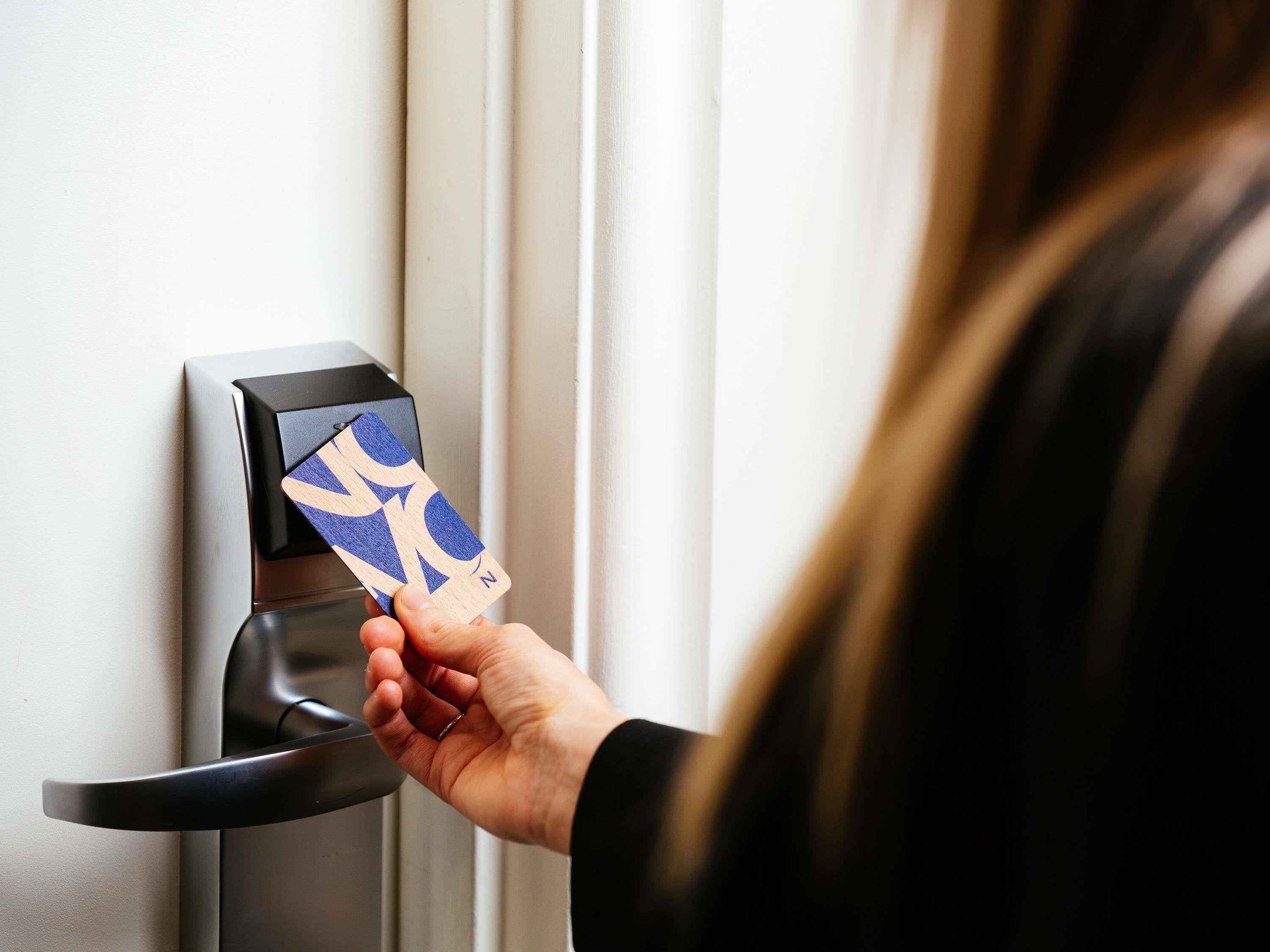 A hand inserting a card into a card reader on a door.