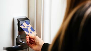 A hand inserting a card into a card reader on a door.