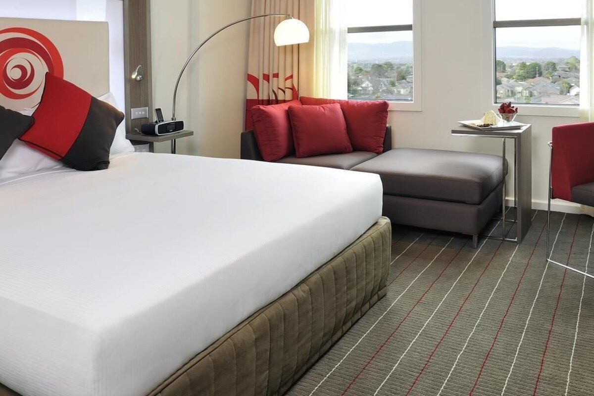 Une chambre d’hôtel avec un lit, un canapé, un bureau et une vue sur la ville.
