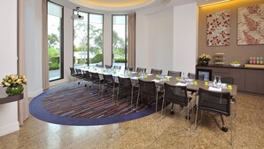 Una sala de conferencias con una larga mesa, sillas y piso alfombrado.