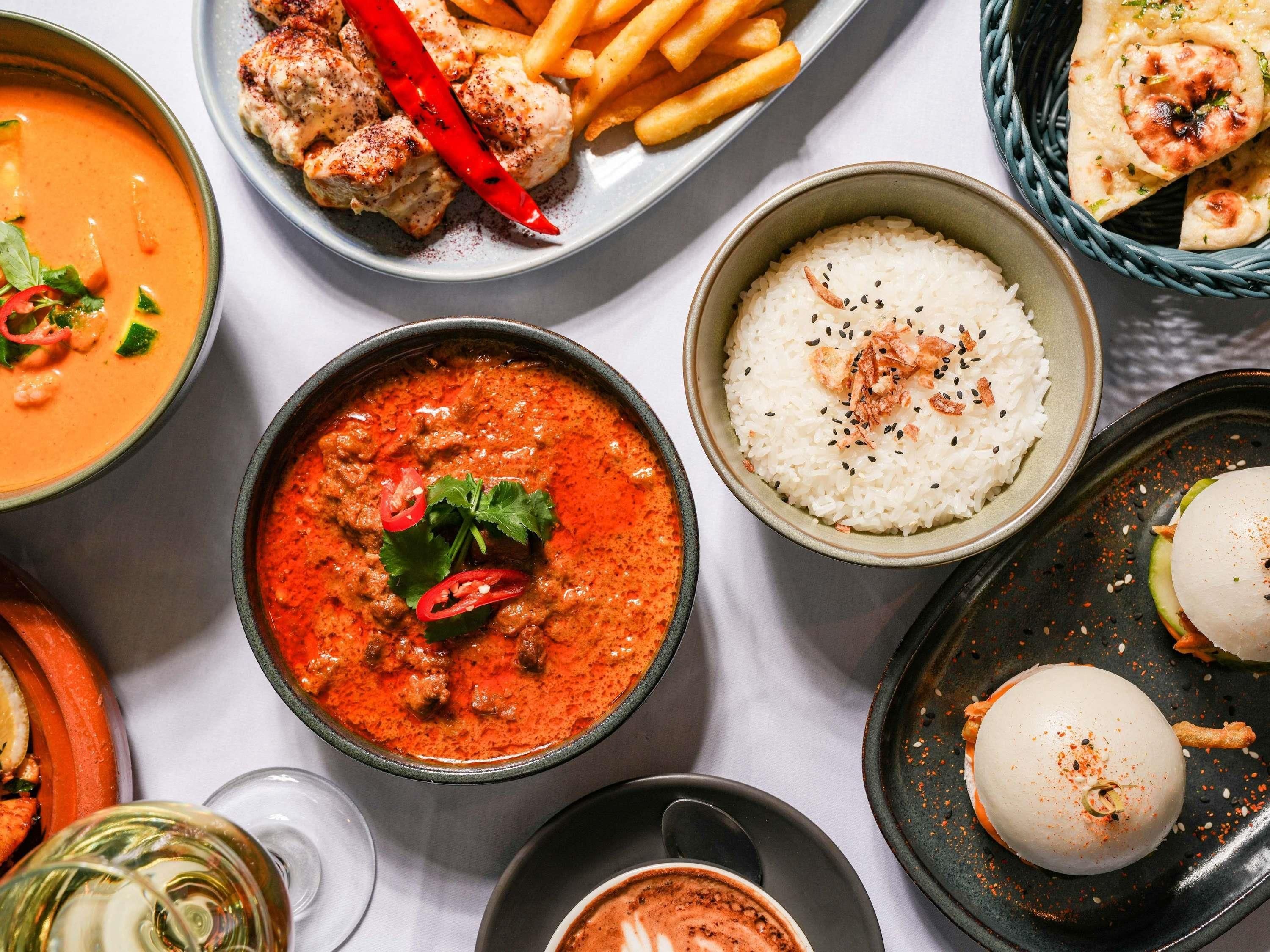 Un assortiment de plats comprenant un bol de soupe, une assiette de boulettes de viande, un bol de riz et une assiette de frites.
