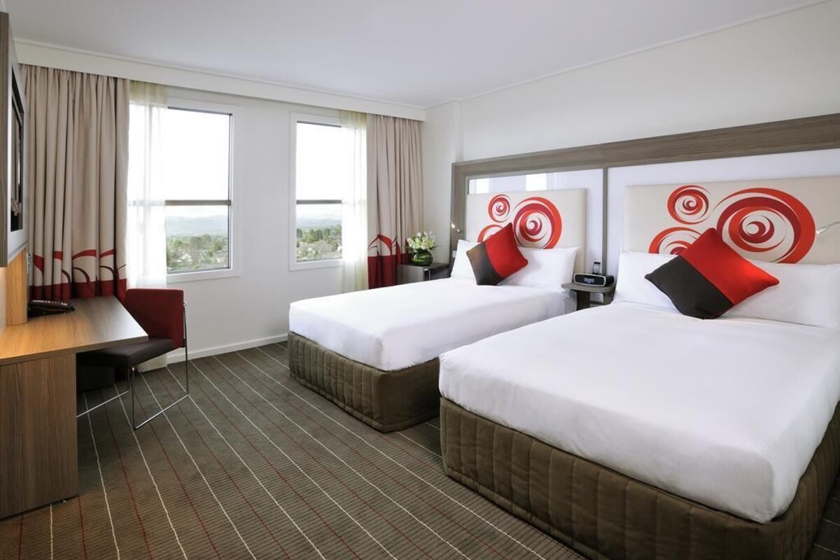 Une chambre d’hôtel avec deux lits, un bureau et une vue sur la ville.