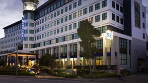 Un hotel moderno con una torre imponente, diversi piani e un ingresso ben illuminato.