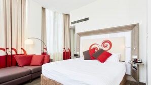 Una habitación de hotel con una cama grande, un sofá, un escritorio y un espejo.