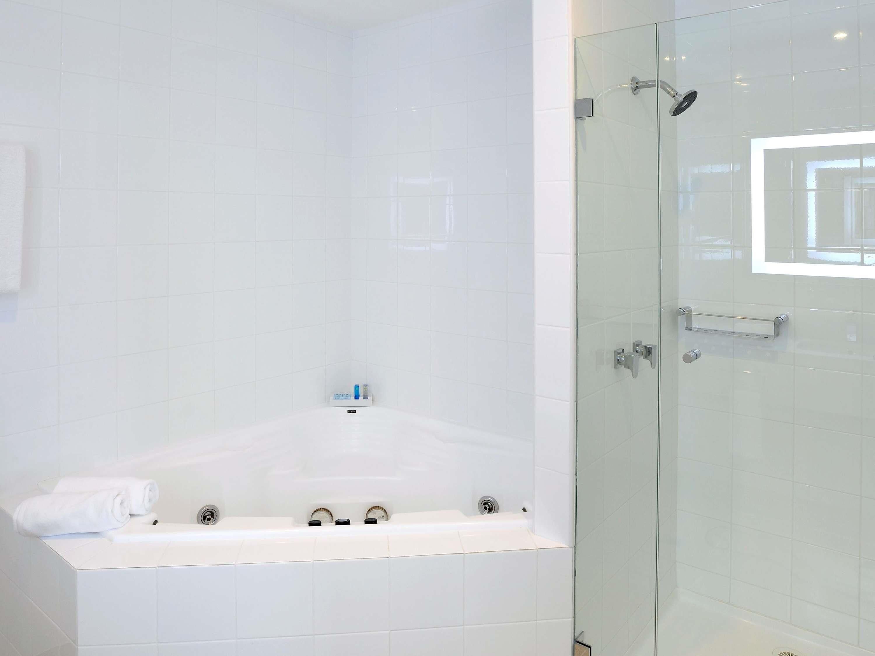 A modern bathroom with a glass-enclosed shower, a white bathtub, and a towel rack.