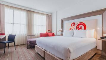 A hotel room with a large bed, a desk, and a chair.