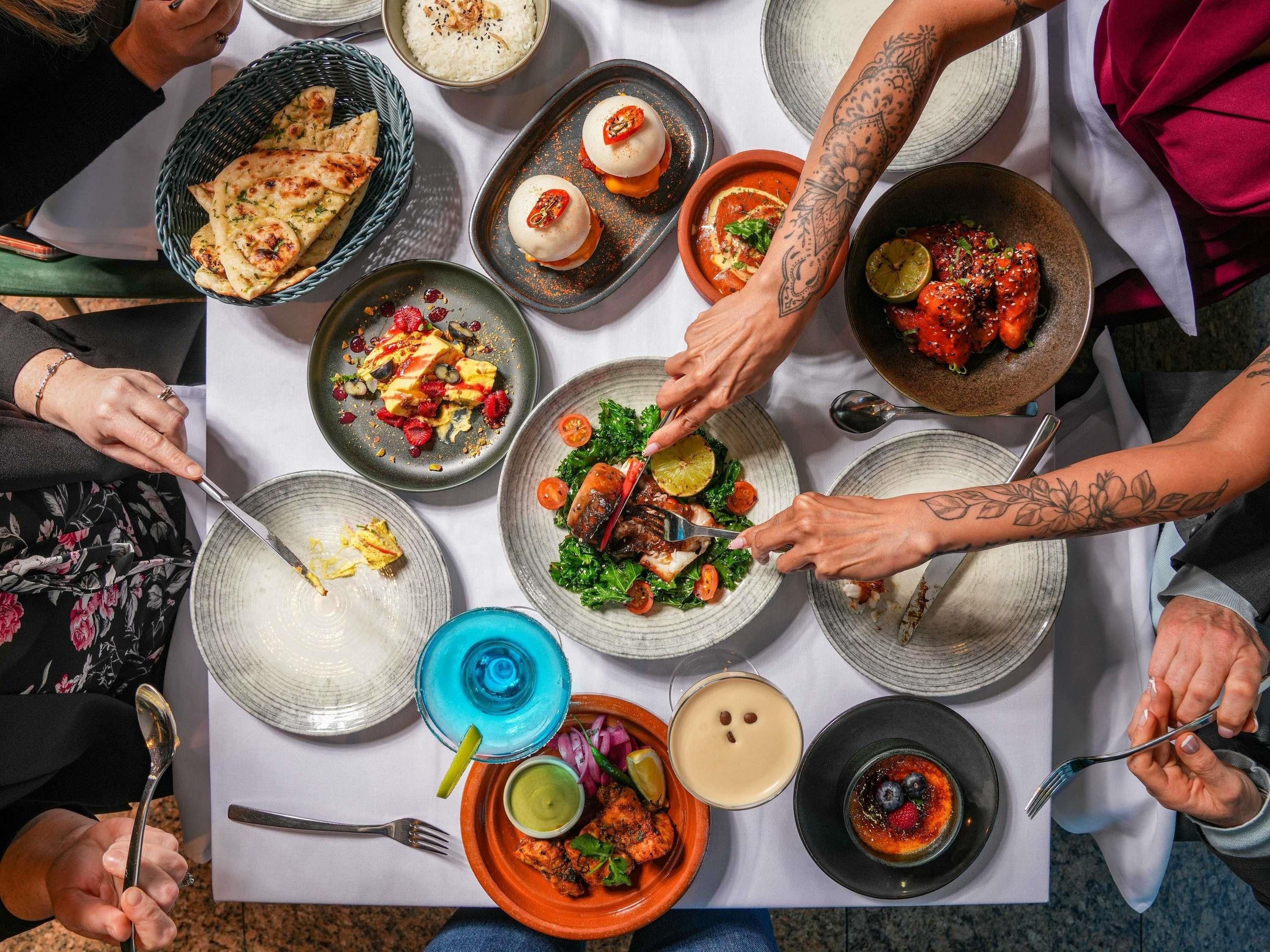 A dining table with various dishes, utensils, and a blue drink.
