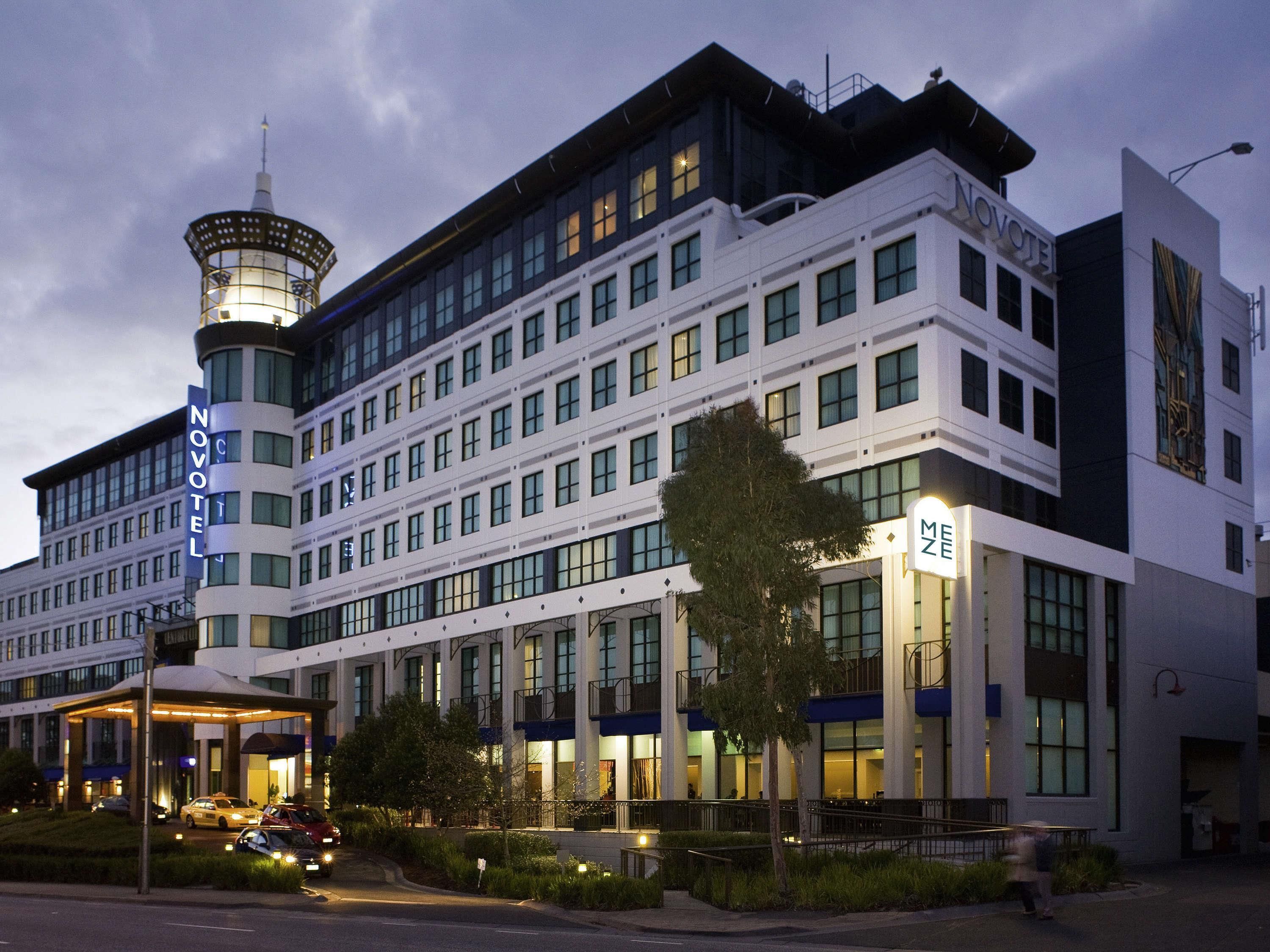 Een modern hotel met een opvallende toren, meerdere verdiepingen en een goed verlichte ingang.