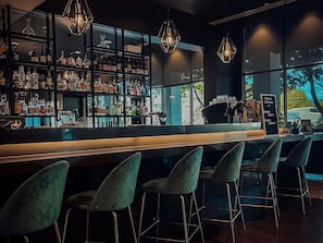 A bar area with a long counter, multiple shelves of bottles, and several bar stools. - Novotel Melbourne Glen Waverley (Glen Waverley)