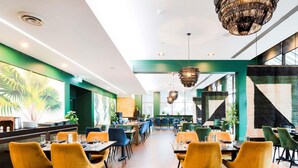 Un ristorante moderno con sedie gialle, pareti verdi e un'ampia vetrata.
