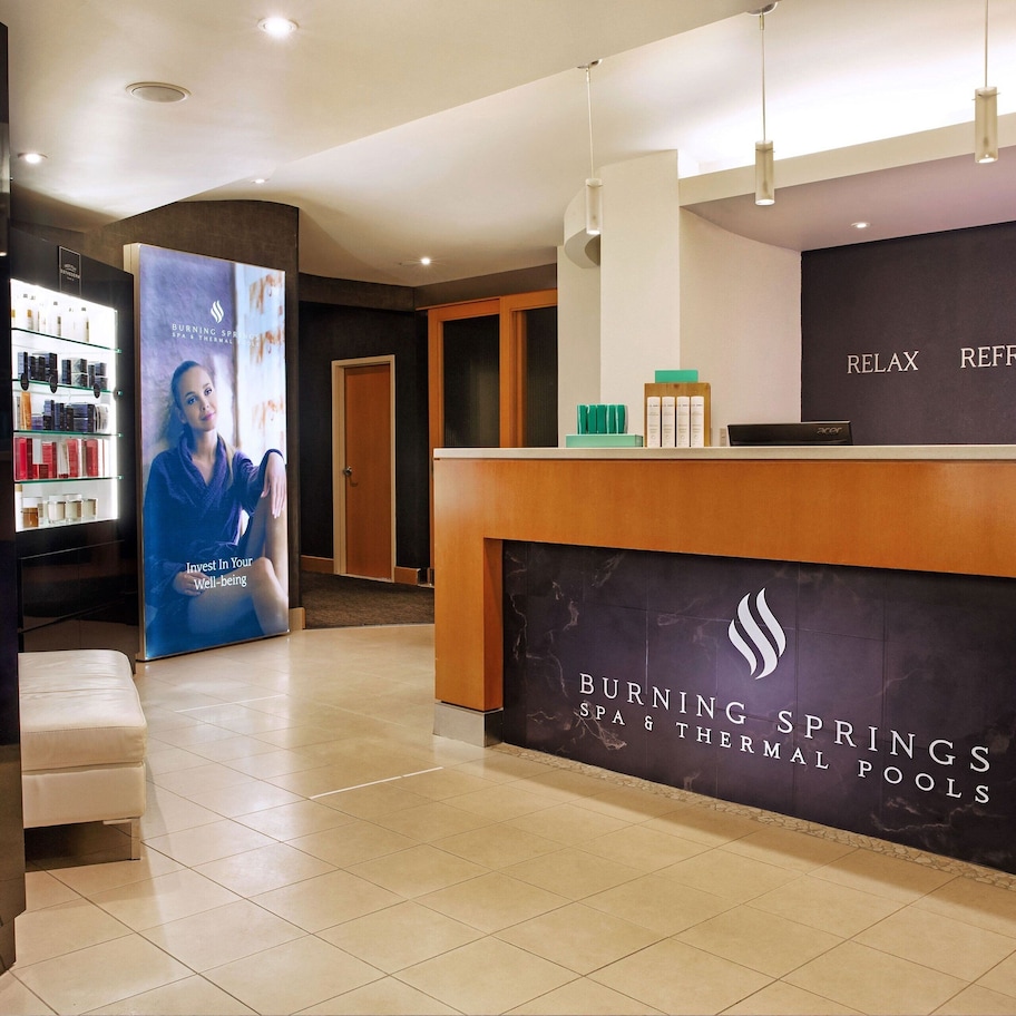 A spa reception area with a reception desk, a glass display of spa products, and a sign for Burning Springs Spa & Thermal Pools.