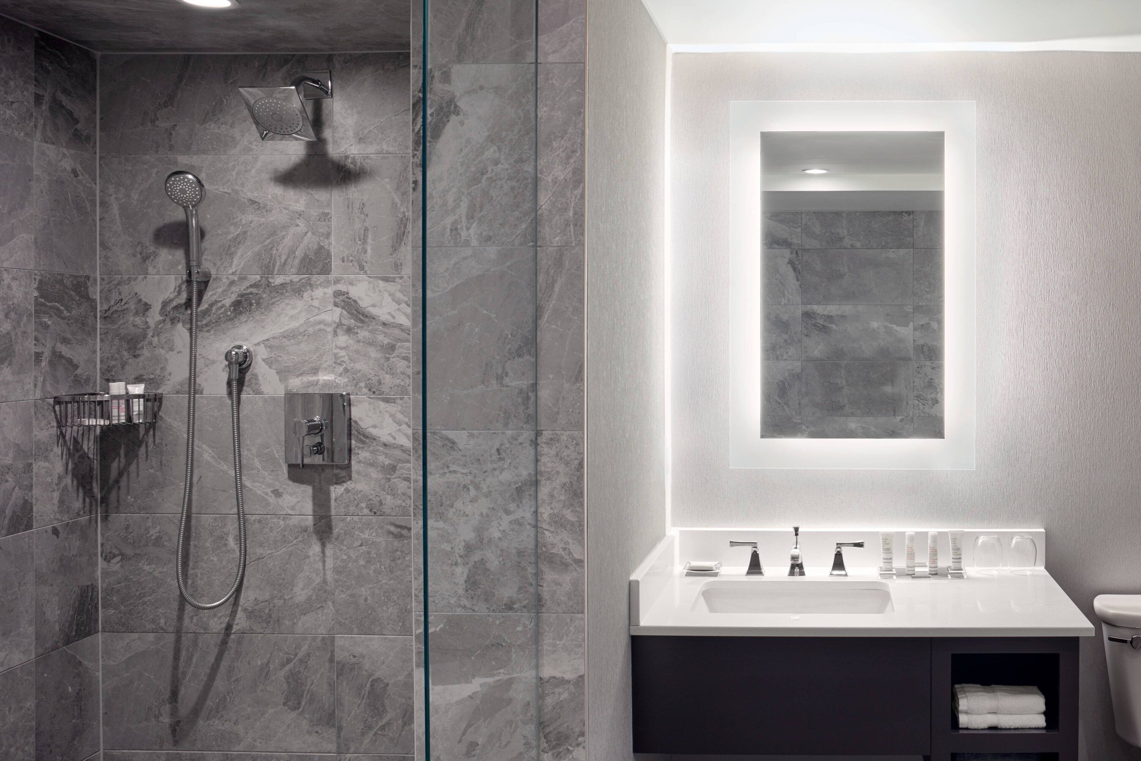 Une salle de bain moderne avec une douche à parois de verre, un lavabo blanc et un grand miroir.