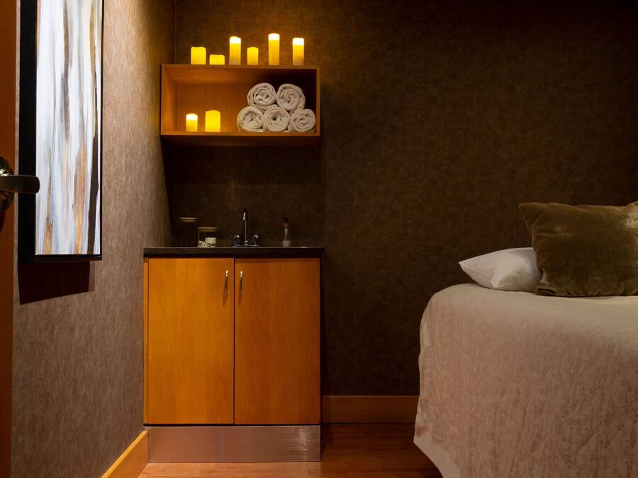 A hotel room with a bed, a wooden cabinet, a shelf with candles, and a window.