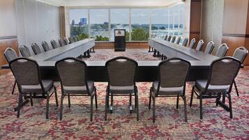 Uma sala de conferência com uma mesa comprida, cadeiras e piso coberto de carpete.